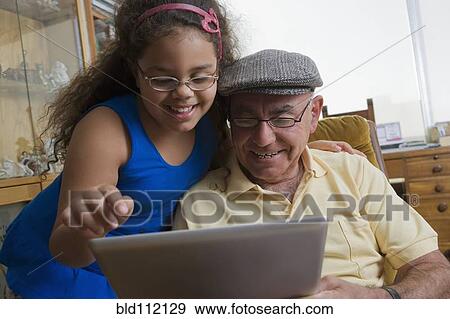 Older Hispanic man using digital tablet with granddaughter View Large Photo Image Stock Photo - Older Hispanic man using digital tablet with granddaughter. Fotosearch