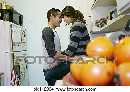 Picture - Smiling couple relaxing in kitchen. Fotosearch