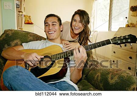 Smiling couple relaxing in living room View Large Photo Image Picture - Smiling couple relaxing in living room. Fotosearch