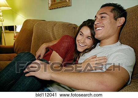 Stock Image - Smiling couple relaxing on sofa. Fotosearch
