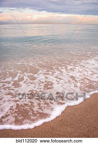 Stock Image - Waves washing up on tropical beach. Fotosearch