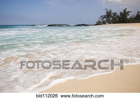 Stock Photograph - Waves washing up on tropical beach. Fotosearch