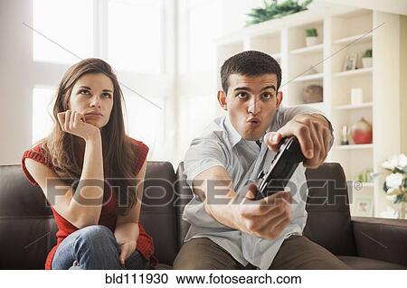 Stock Image - Woman watching boyfriend play video games. Fotosearch
