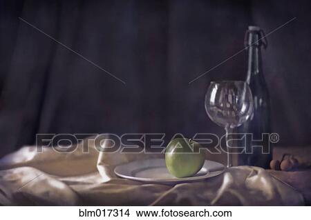 Picture - Apple, wine glass and bottle on tablecloth. Fotosearch