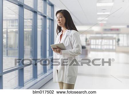 Stock Image - Asian doctor walking in hospital. Fotosearch
