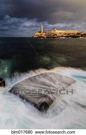 Stock Image - Blurred view of water washing over rock in harbor. Fotosearch