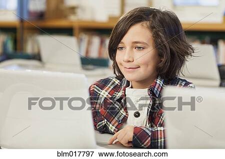 Stock Photo - Caucasian boy using laptop in library. Fotosearch