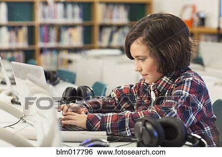 Stock Photograph - Caucasian boy using laptop in library. Fotosearch