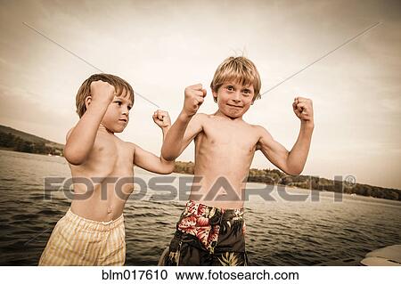 Caucasian boys flexing muscles on wooden dock View Large Photo Image Stock Image - Caucasian boys flexing muscles on wooden dock. Fotosearch