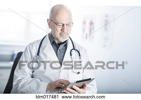 Stock Image - Caucasian doctor using tablet computer in office. Fotosearch