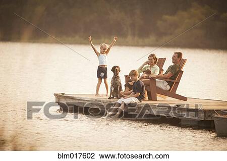 Stock Image - Caucasian family relaxing on pier. Fotosearch