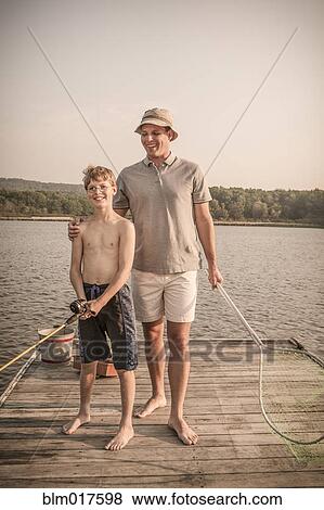 Stock Photo - Caucasian father and son holding tennis rackets. Fotosearch