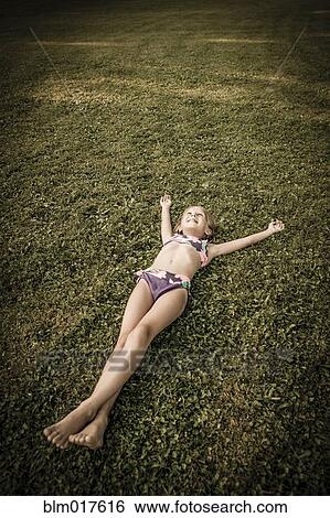 Stock Photograph - Caucasian girl laying in grassy field. Fotosearch