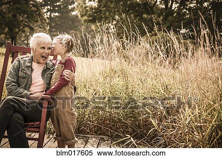 Caucasian girl whispering to grandmother outdoors View Large Photo Image Stock Photography - Caucasian girl whispering to grandmother outdoors. Fotosearch