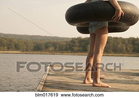 Caucasian girls with inner tubes on wooden dock View Large Photo Image Stock Photo - Caucasian girls with inner tubes on wooden dock. Fotosearch
