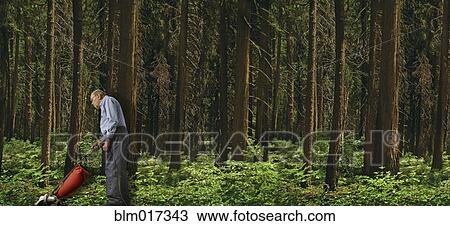 Stock Image - Caucasian man vacuuming forest floor. Fotosearch