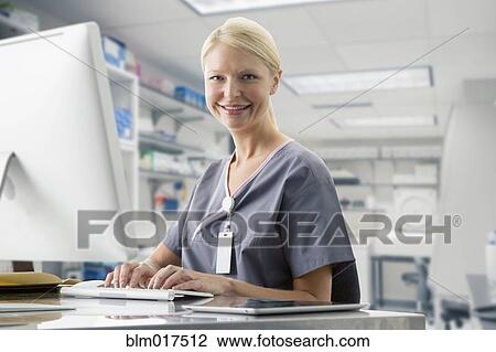 Stock Image - Caucasian nurse working at computer in hospital. Fotosearch