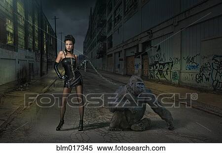 Stock Photography - Caucasian woman with gorilla on chain on city street. Fotosearch