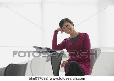Stock Image - Chinese businesswoman smiling at desk. Fotosearch