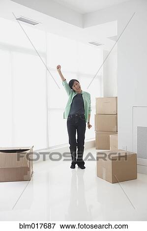 Stock Photo - Chinese woman cheering in new home. Fotosearch