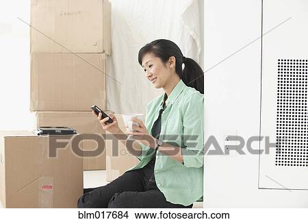 Picture - Chinese woman with boxes in new home. Fotosearch