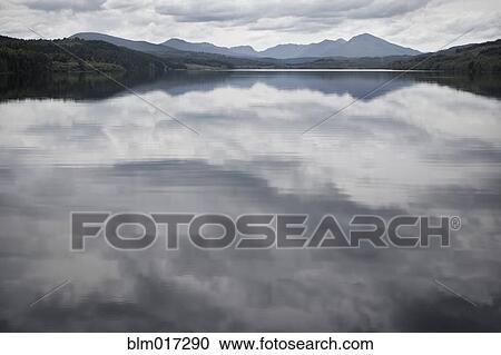 Cloudy sky reflected in still rural lake View Large Photo Image Stock Image - Cloudy sky reflected in still rural lake. Fotosearch