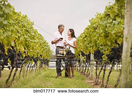 Stock Photo - Couple tasting wine together in vineyard. Fotosearch