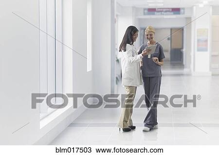 Stock Image - Doctor and nurse talking in hospital. Fotosearch