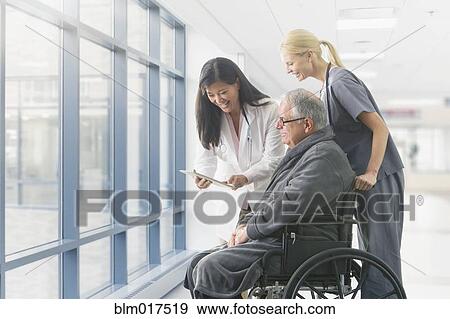 Stock Photo - Doctor and nurse talking to patient in hospital. Fotosearch