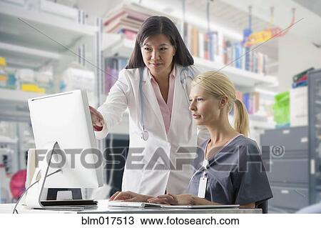 Stock Image - Doctor and nurse working at computer in hospital. Fotosearch