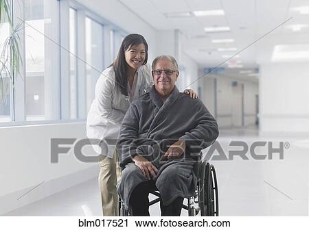 Stock Image - Doctor smiling with patient in hospital. Fotosearch