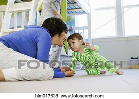 Stock Photo - Hispanic mother with toddler in bedroom. Fotosearch