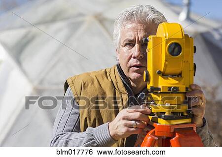 Stock Photograph - Hispanic surveyor working outdoors. Fotosearch