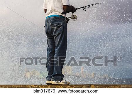 Man fishing off concrete wall View Large Photo Image Stock Photo - Man fishing off concrete wall. Fotosearch