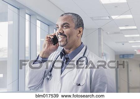 Mixed race doctor talking on cell phone in hospital View Large Photo Image Stock Photo - Mixed race doctor talking on cell phone in hospital. Fotosearch