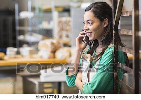 Stock Photo - Mixed race woman working in bakery kitchen. Fotosearch
