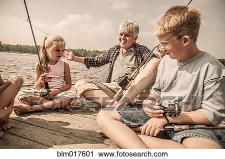 Stock Image - Older Caucasian man teaching grandchildren to fish. Fotosearch