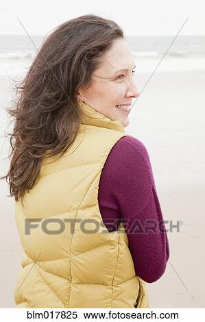 Stock Photography - Older Caucasian woman walking on beach. Fotosearch