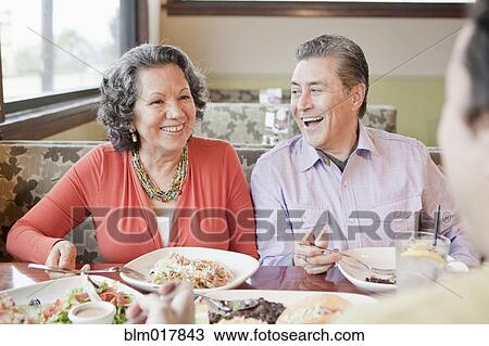 Stock Image - Older Hispanic couple having dinner in restaurant. Fotosearch