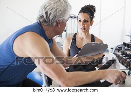 Older Hispanic man working with trainer in gym View Large Photo Image Stock Photo - Older Hispanic man working with trainer in gym. Fotosearch