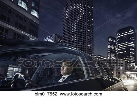Stock Image - Pacific Islander businessman driving on city street. Fotosearch