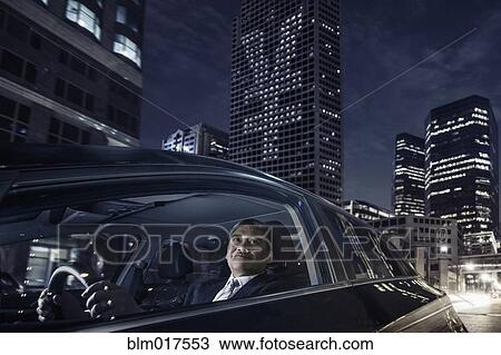 Stock Image - Pacific Islander businessman driving on city street. Fotosearch