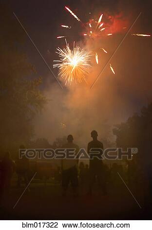 Stock Image - People watching fireworks in night sky. Fotosearch