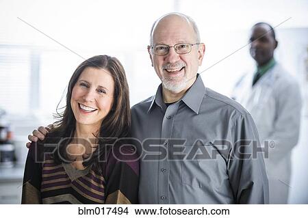 Smiling couple standing in doctor's office View Large Photo Image Picture - Smiling couple standing in doctor's office. Fotosearch