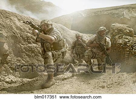 Stock Image - Soldiers advancing in dry rural landscape. Fotosearch