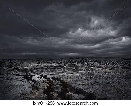 Stock Photograph - Storm clouds over dry rocky landscape. Fotosearch
