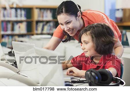 Teacher and student using laptop in library View Large Photo Image Stock Photo - Teacher and student using laptop in library. Fotosearch