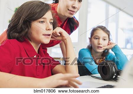 Teacher and students using laptop in library View Large Photo Image Stock Photograph - Teacher and students using laptop in library. Fotosearch