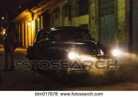Vintage car driving on city street at night View Large Photo Image Stock Photo - Vintage car driving on city street at night. Fotosearch