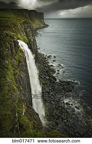 Stock Image - Waterfall over rocky cliff and sea. Fotosearch